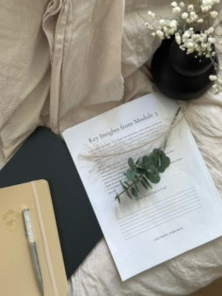 Sheet of paper with text and a plant on a bed with a notebook and pen.